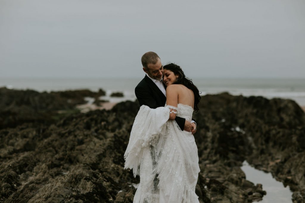 A bride and groom hug each other tightly on the beach during their intimate wedding in Cornwall 