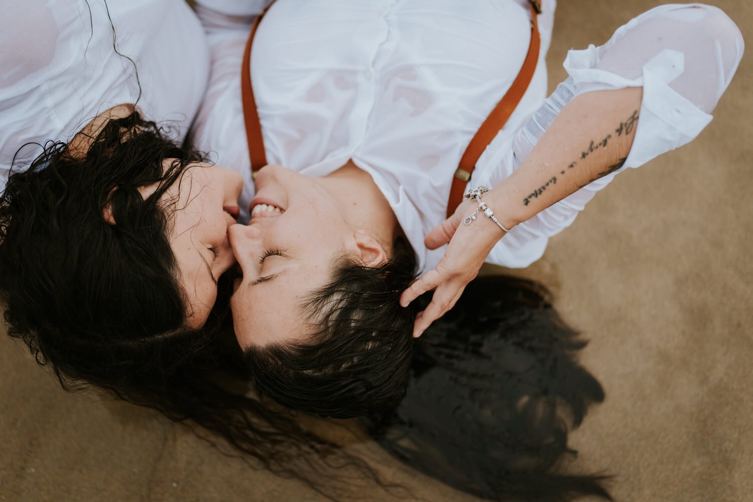 same sex couple kissing in the sea at Crantock beach Cornwall